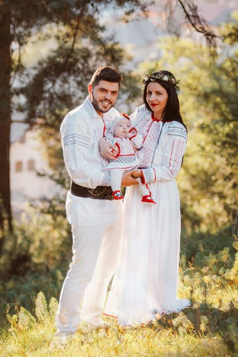 Familie in tinute traditionale cu copilul la un eveniment de botez